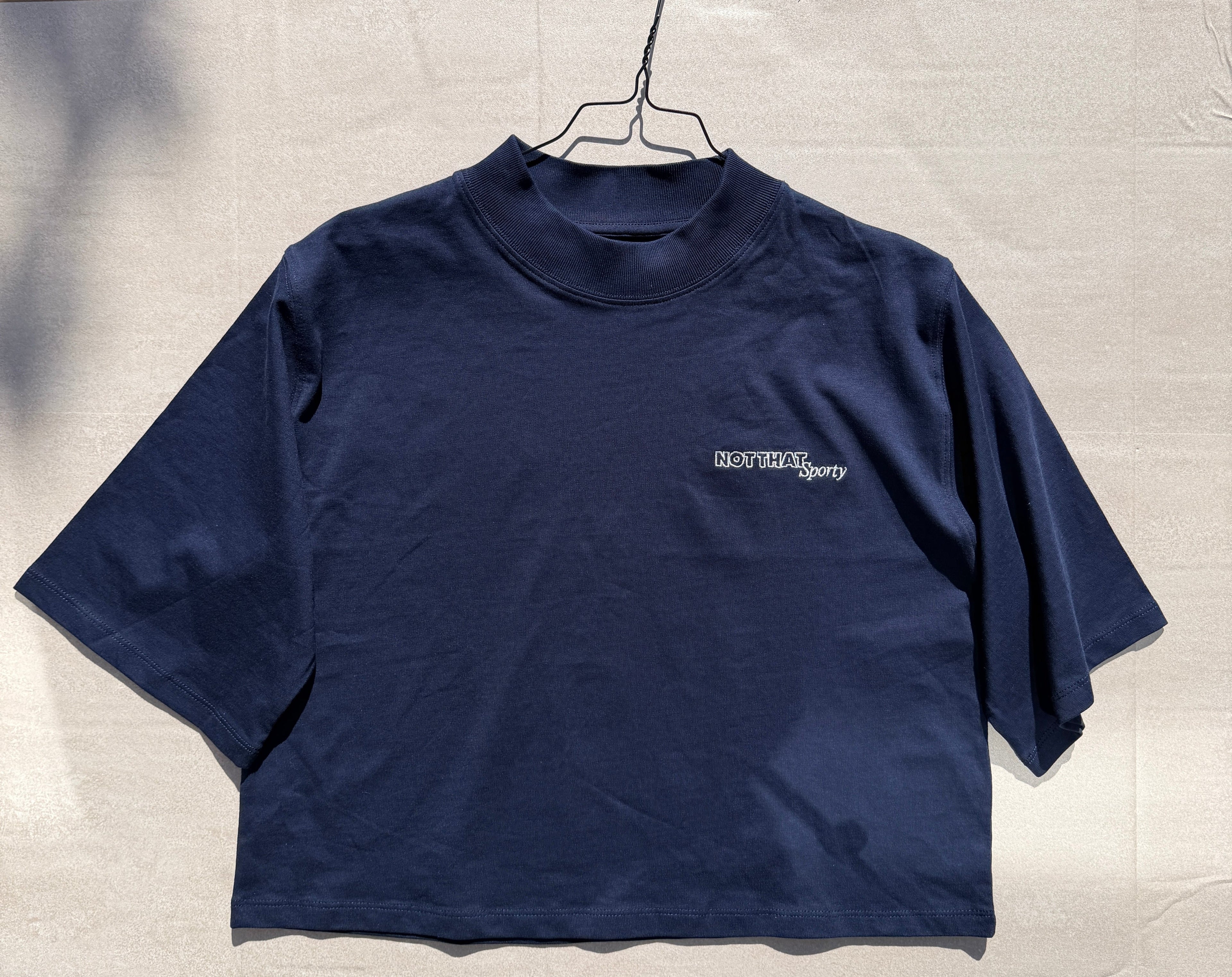 Navy blue sleeveless shirt with a brand logo on a light beige background